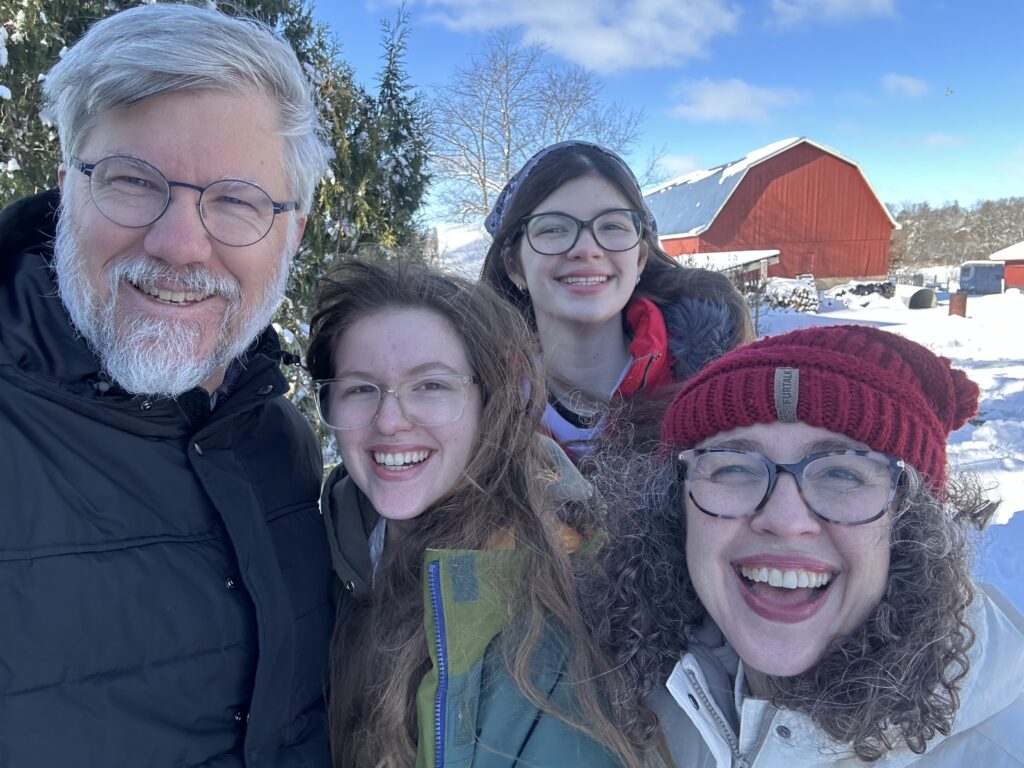 Photo of Jon, Lucy, Rosie, and Ann Boyd on a snowy day with a red barn in the background